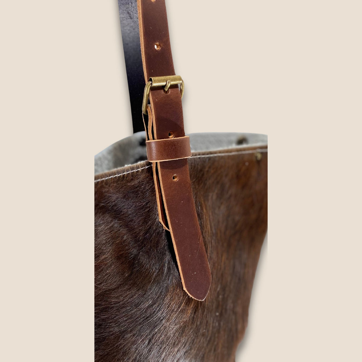Détail de la lanière en cuir marron du cabas Salers #27/160, avec boucle métallique et trous de réglage.