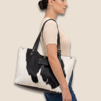 Cabas Holstein #27/163 noir et blanc porté à l’épaule par un modèle, avec anses en cuir noir.