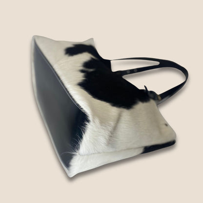 Vue du dessous du cabas Holstein #27/163, avec fond rectangulaire en cuir noir bordé de peau blanche.
