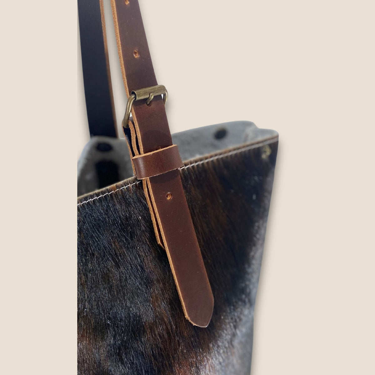 Détail de l’anse en cuir marron du cabas #27/159, avec boucle métallique, passant et trous de réglage.