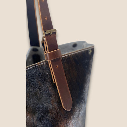Détail de l’anse en cuir marron du cabas #27/159, avec boucle métallique, passant et trous de réglage.