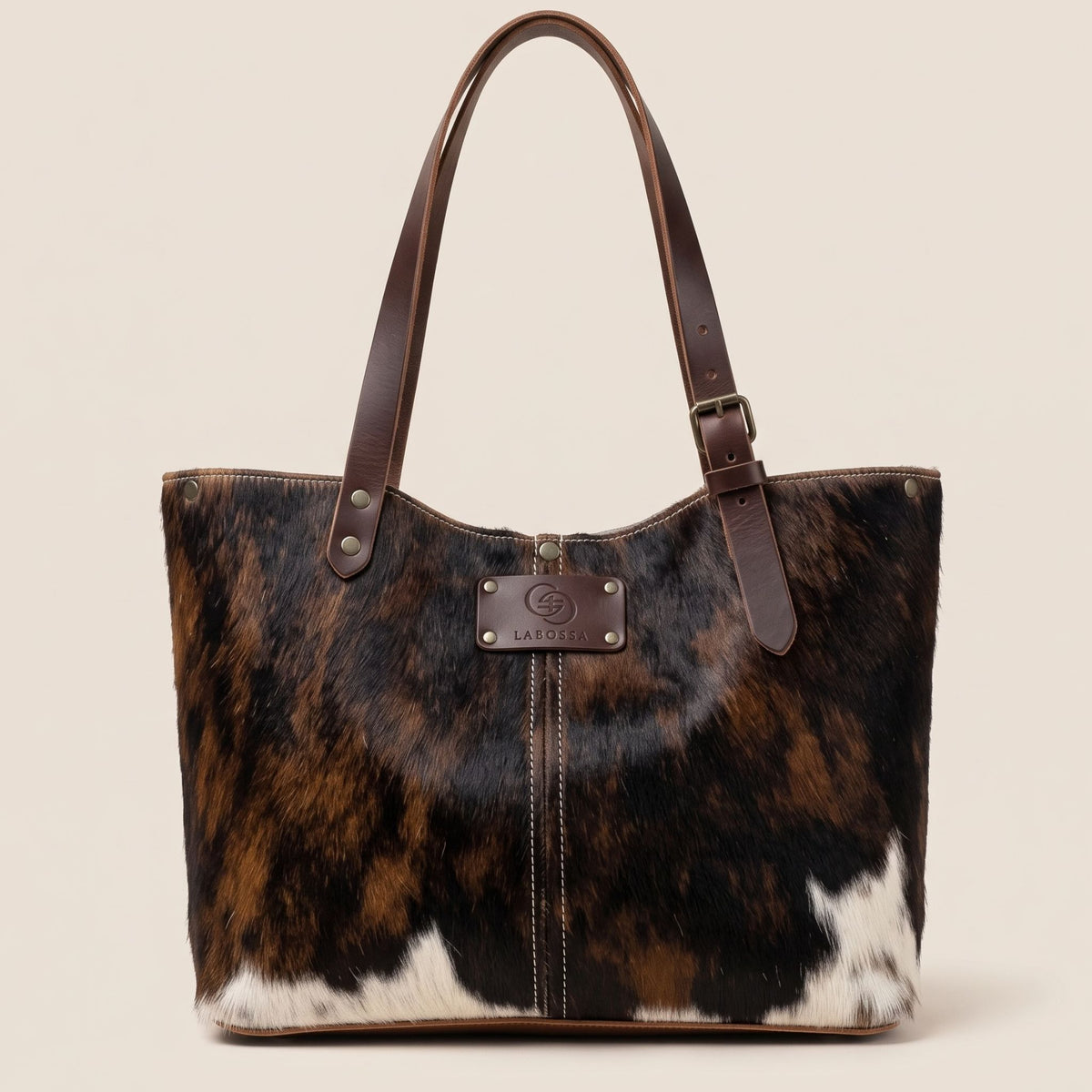 Cabas en peau de vache naturelle normande #27/159, robe noire, brune et blanche, avec anses en cuir marron.
