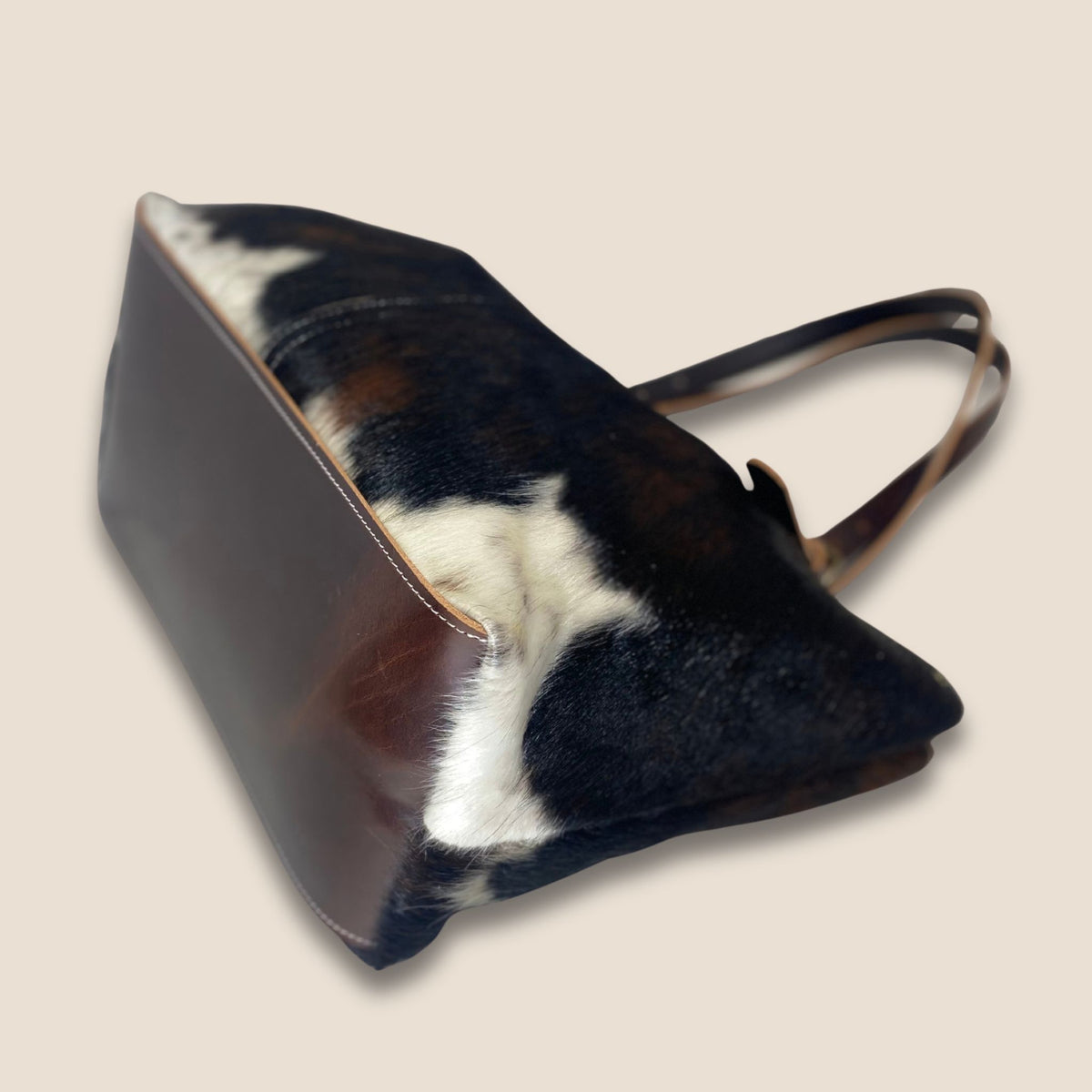 Fond en cuir marron du cabas normande #27/159, avec couture périphérique et peau noire et blanche sur les côtés.