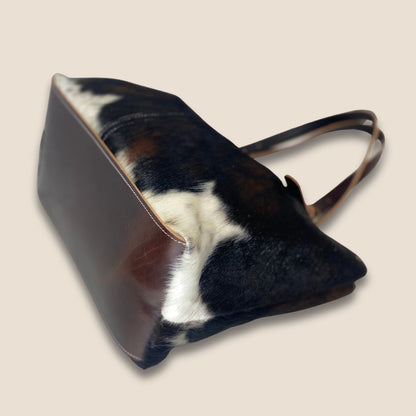 Fond en cuir marron du cabas normande #27/159, avec couture périphérique et peau noire et blanche sur les côtés.