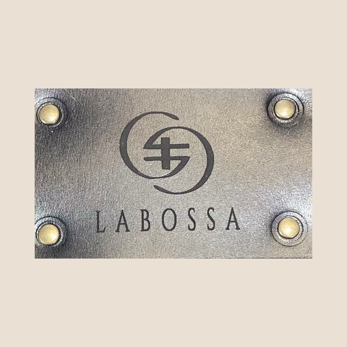 Gros plan du patch extérieur en cuir noir, gravé du logo Labossa et fixé par quatre rivets.
