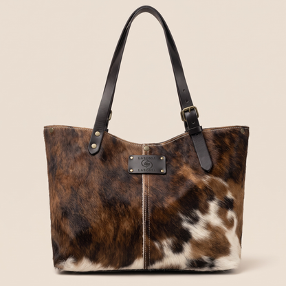 Cabas peau de vache Normande 27/162 vu de face, robe brune et blanche, lanières et patch en cuir noir Primavera.