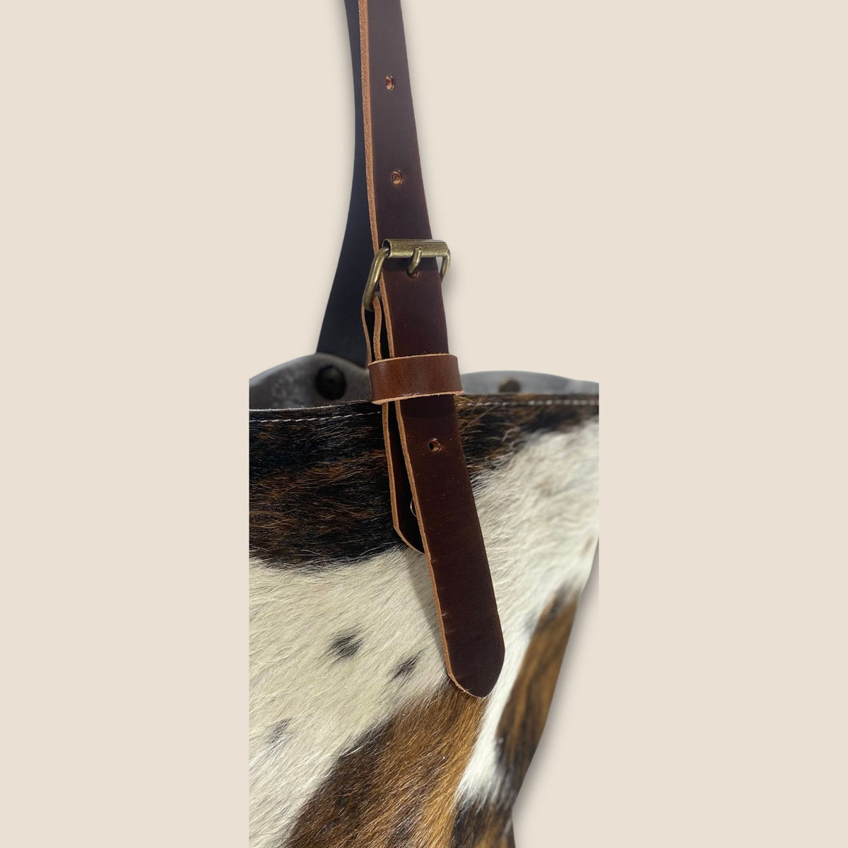  Détail d’une anse en cuir marron du cabas Normande n° 27/164, avec boucle métallique et trous de réglage.