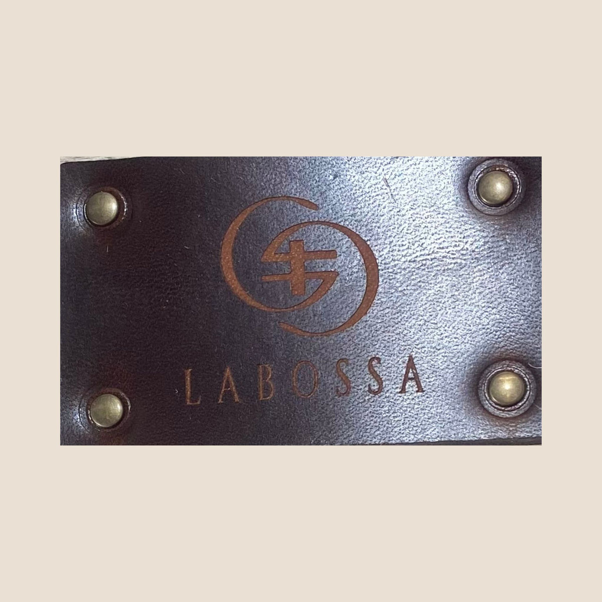 Gros plan du patch extérieur en cuir marron, gravé du logo Labossa et fixé par quatre rivets.