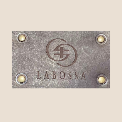 Gros plan du patch extérieur en cuir lisse Primavera marron, gravé du logo Labossa et fixé par quatre rivets.
