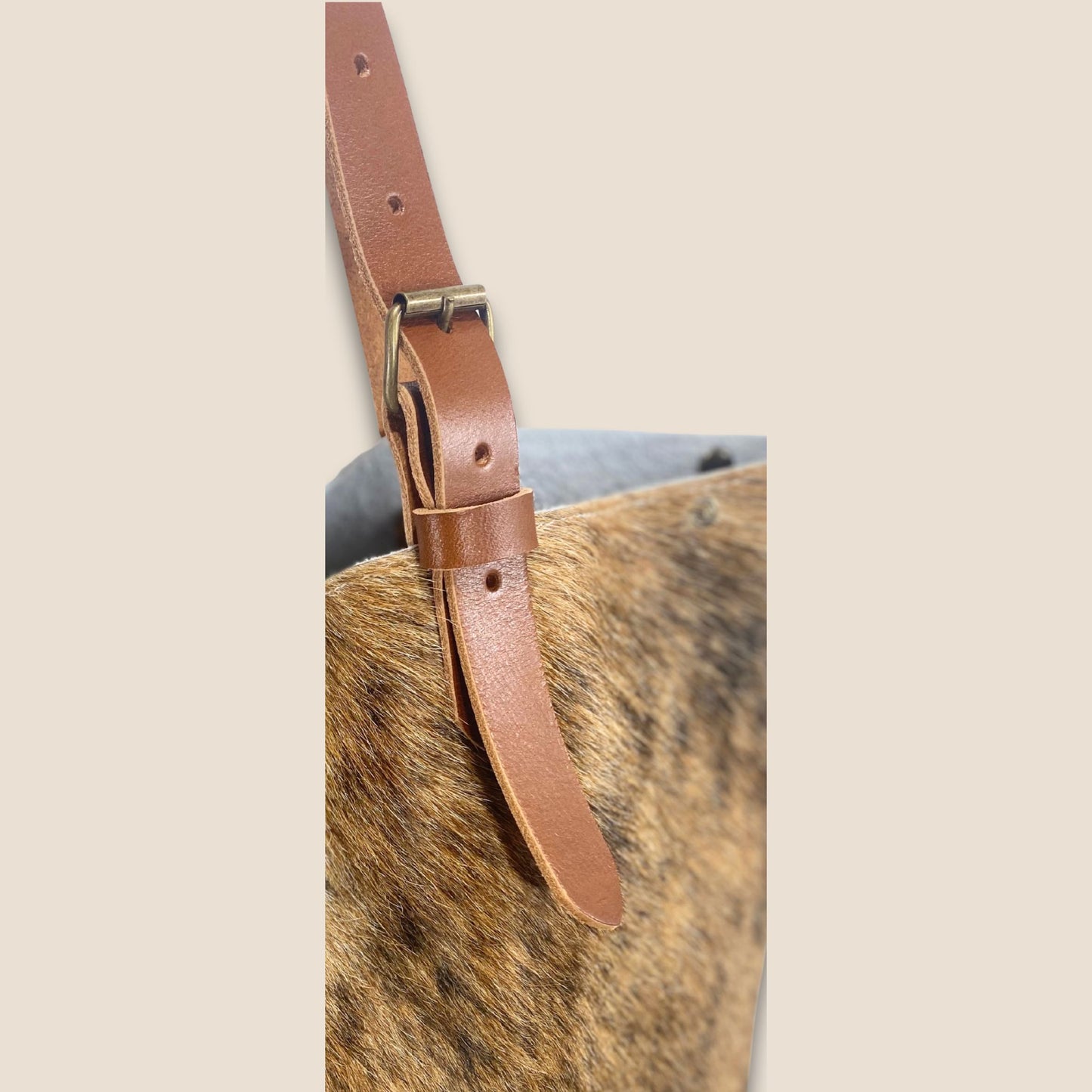 Gros plan sur la lanière en cuir cognac du cabas en peau de vache Saïnata #27/148.