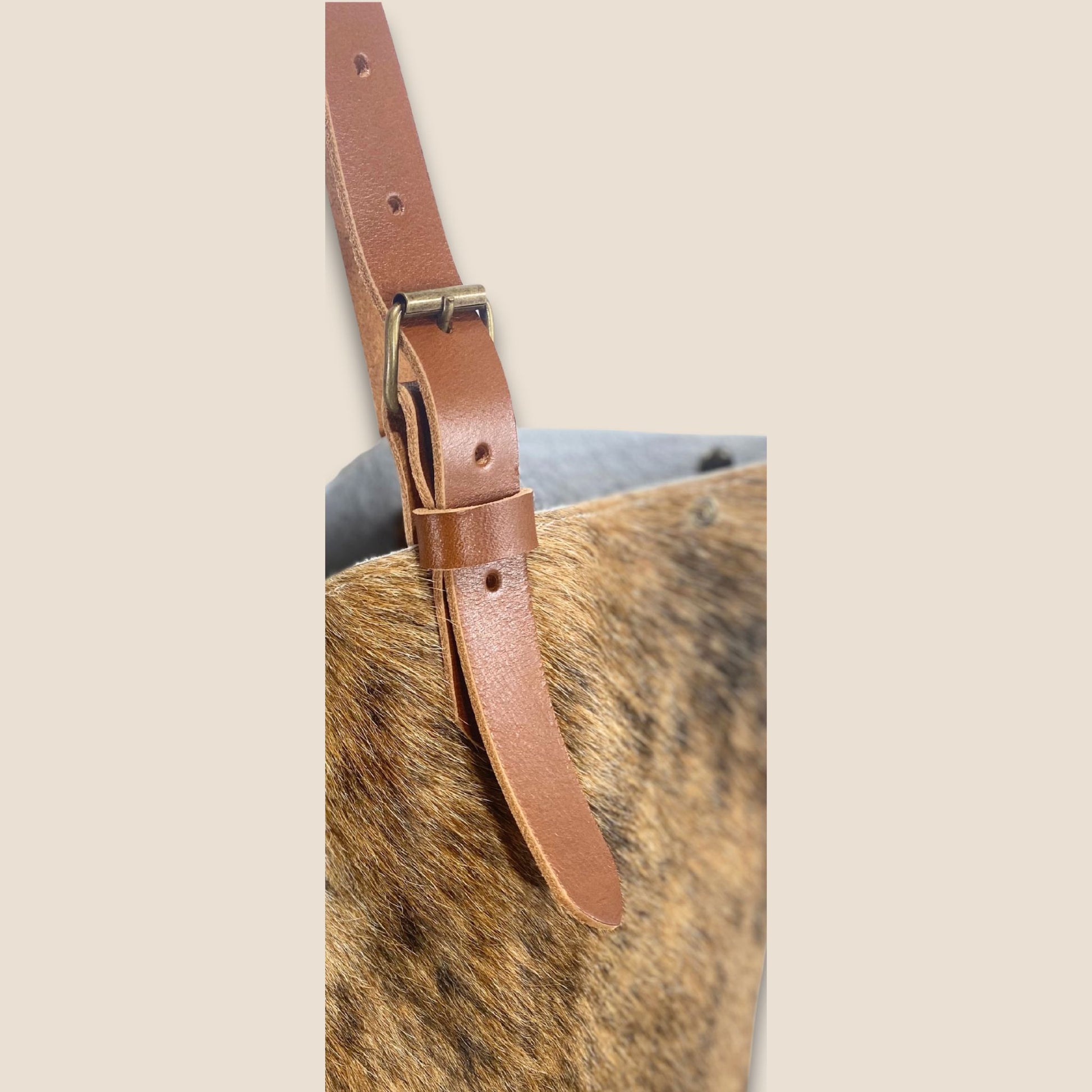 Gros plan sur la lanière en cuir cognac du cabas en peau de vache Saïnata #27/148.