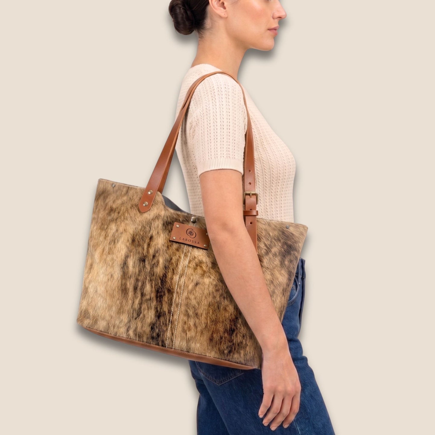 Cabas en peau de vache naturelle Saïnata #27/148 porté par un modèle, avec lanière en cuir cognac.