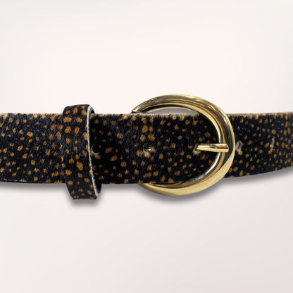 Gros plan sur la boucle dorée et la texture riche du cuir poil de vache au motif léopard de la ceinture Savana, maroquinerie de qualité faite main.