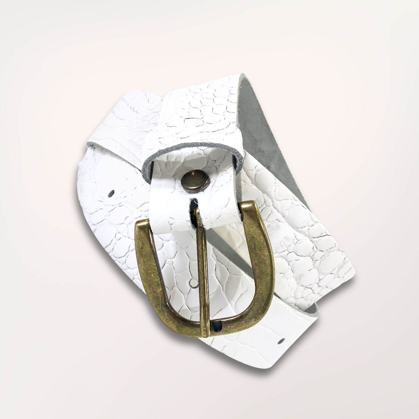 Ceinture artisanale blanche en cuir façon caïman enroulée, mettant en avant la souplesse du cuir et la qualité de la boucle dorée.