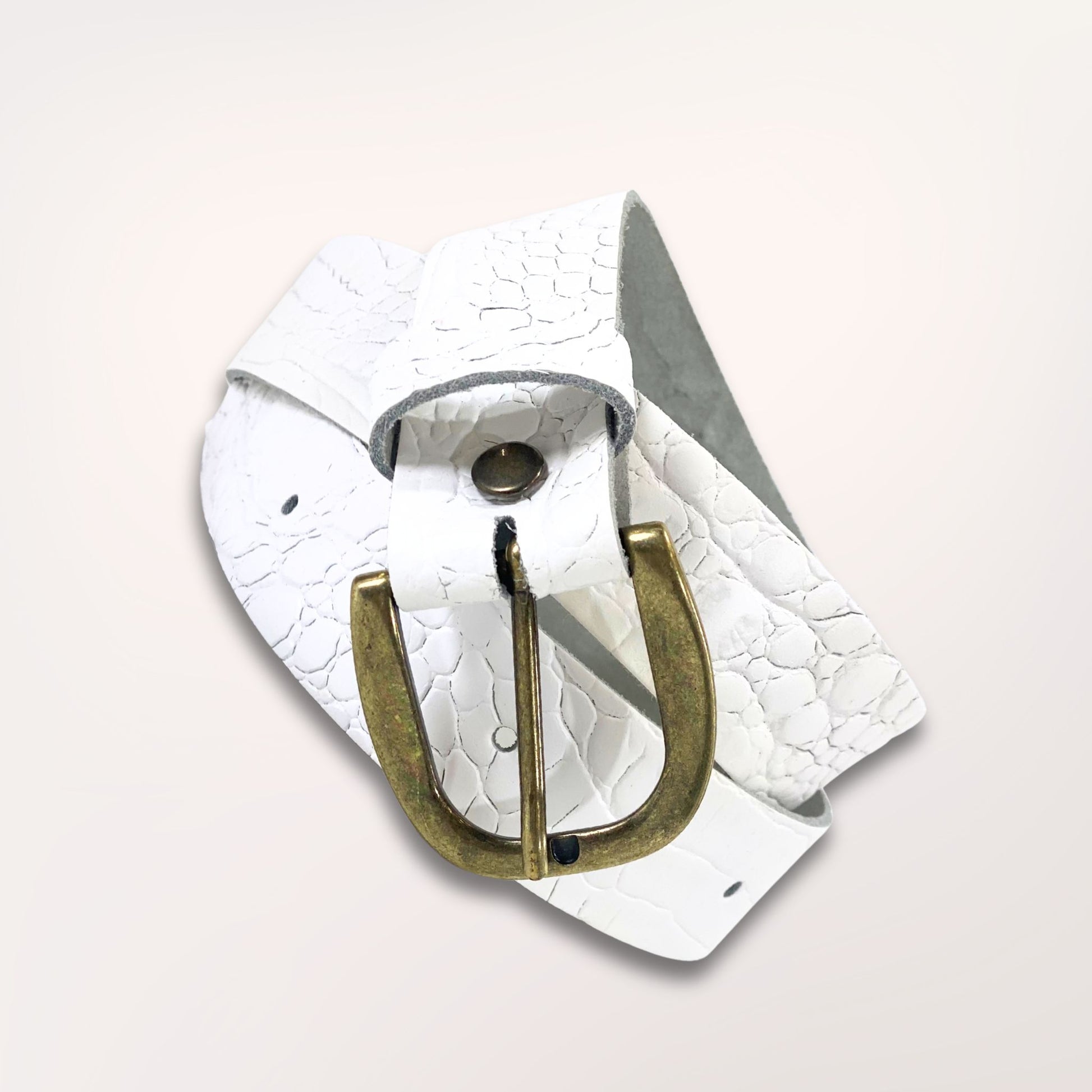 Ceinture artisanale blanche en cuir façon caïman enroulée, mettant en avant la souplesse du cuir et la qualité de la boucle dorée.