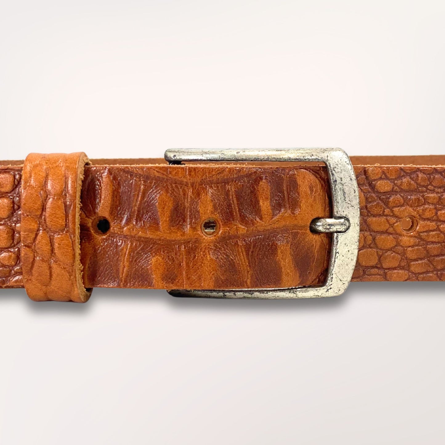 Gros plan sur la texture cuir cognac embossé caïman et la boucle de la ceinture Primavera, finition artisanale Labossa.