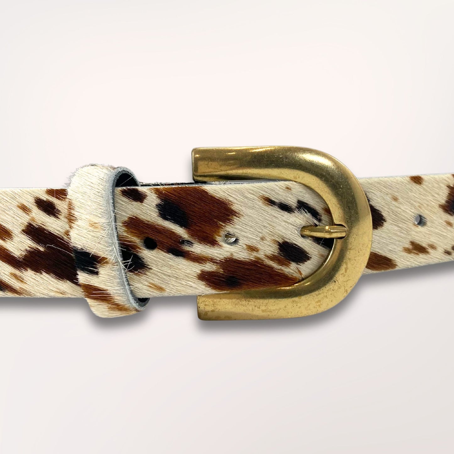 Gros plan sur la boucle argentée et le cuir poil de vache au motif Ouest Sauvage, avec taches marron et noir, maroquinerie faite main dans l'atelier Labossa à Roubaix.