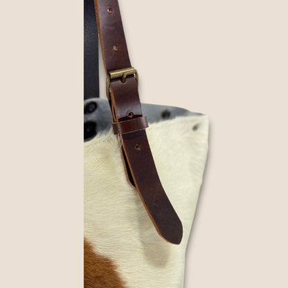 Gros plan sur la lanière réglable en cuir marron chocolat et sa boucle métallique, fixée sur le cabas en peau naturelle normande #13/147.