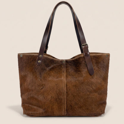 Cabas en peau de vache naturelle normande #13/147 vu de dos, avec une robe principalement brune, une couture centrale et des anses en cuir chocolat.