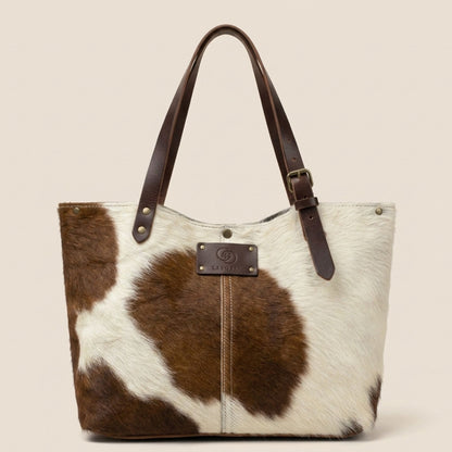 Cabas en peau de vache naturelle normande #13/147, vue de face, robe blanche et brune, anses en cuir marron chocolat et plaque Labossa.