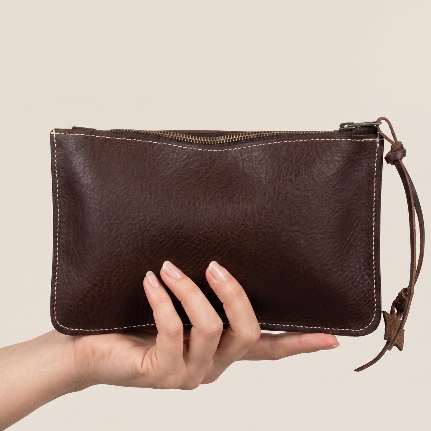 Pochette cuir Minerva chocolat tenue en main – format plat 24x15 cm, tannage végétal Badalassi Carlo