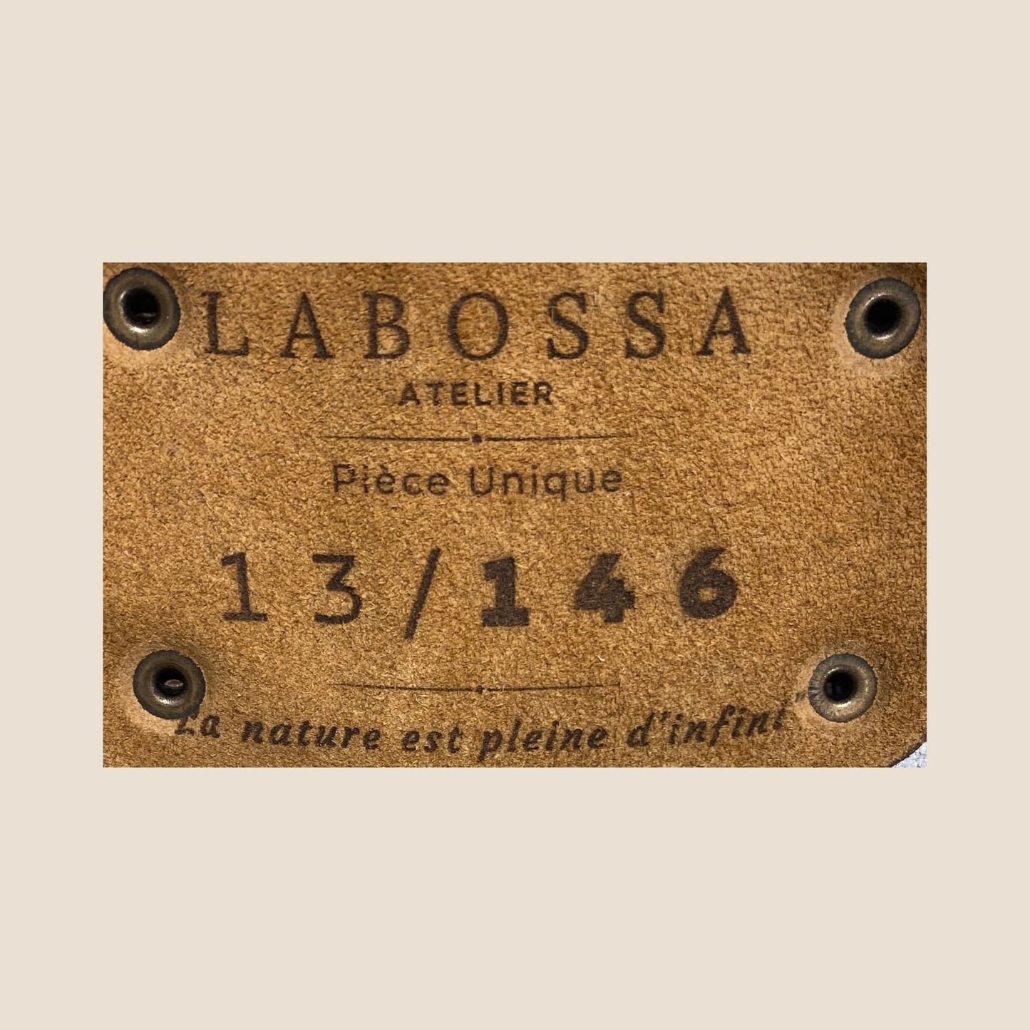 Gros plan sur la plaque extérieure en cuir marron portant le logo Labossa, fixée sur le cabas en peau de vache naturelle #13/146.