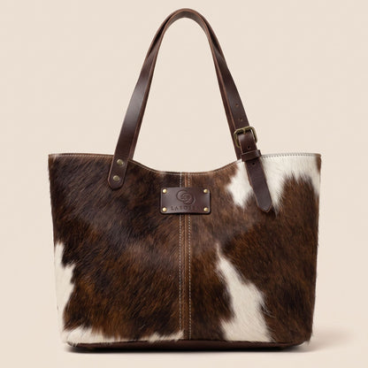 Cabas en peau de vache naturelle normande #13/146, vue de face, robe brun foncé avec des marques blanches et anses en cuir marron chocolat.