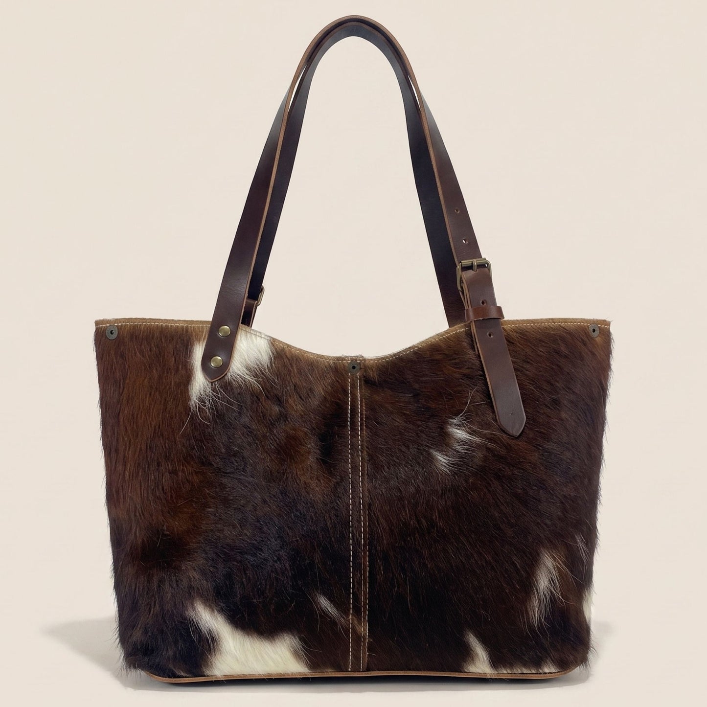 Cabas en peau de vache naturelle normande #13/146 vu de dos, avec une robe brun foncé, des marques blanches et une couture centrale.
