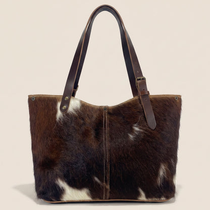 Cabas en peau de vache naturelle normande #13/146 vu de dos, avec une robe brun foncé, des marques blanches et une couture centrale.